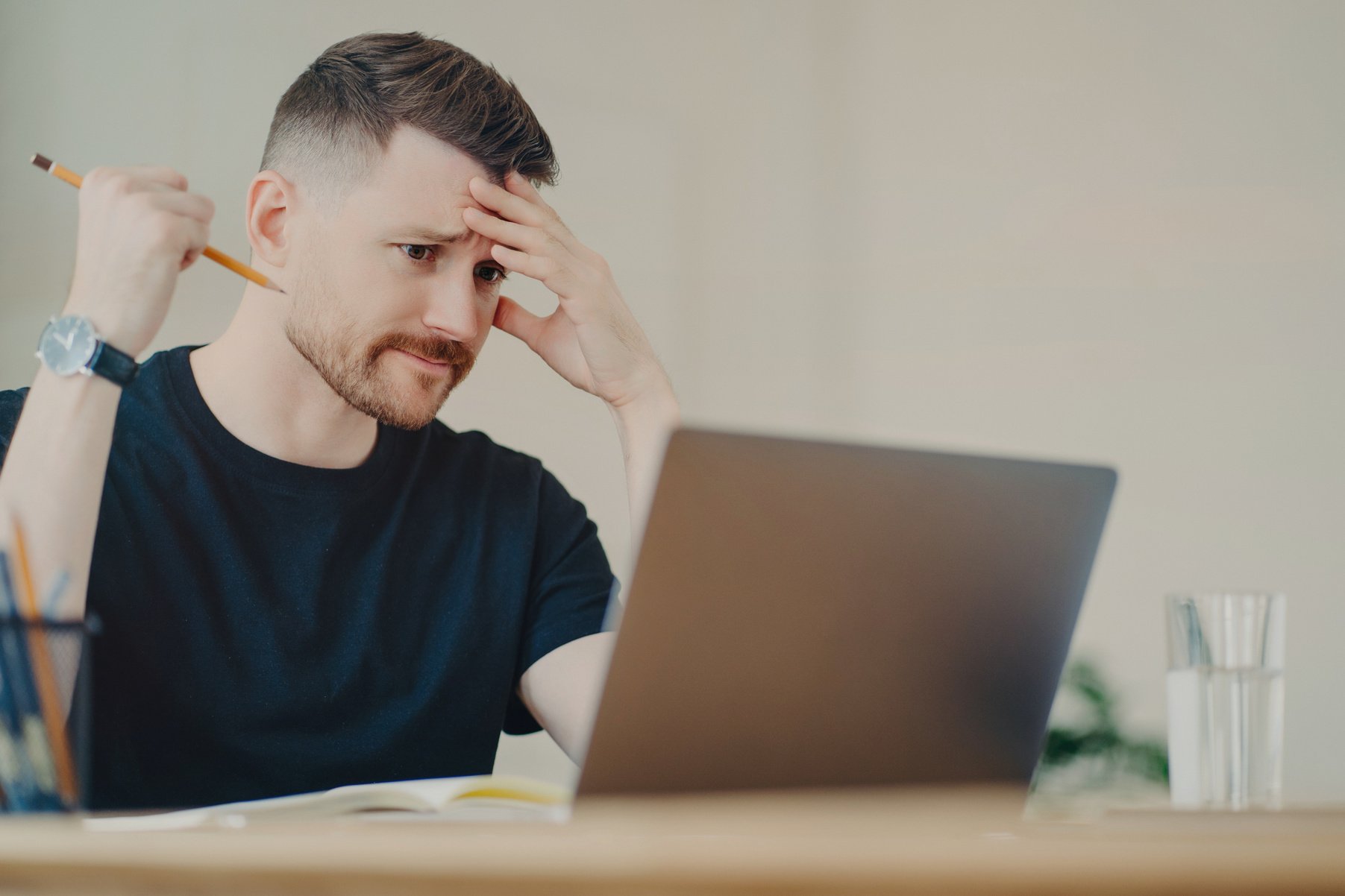 Stressed male office worker looking at laptop with worried f